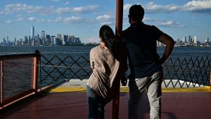 A couple stand on the deck of the Staten Island ferry in front of the Lower Manhattan skyline. Staten Island is not on the New York City Subway system and can only be reached by car or ferry. Photo: Johannes Eisele/AFP/Getty