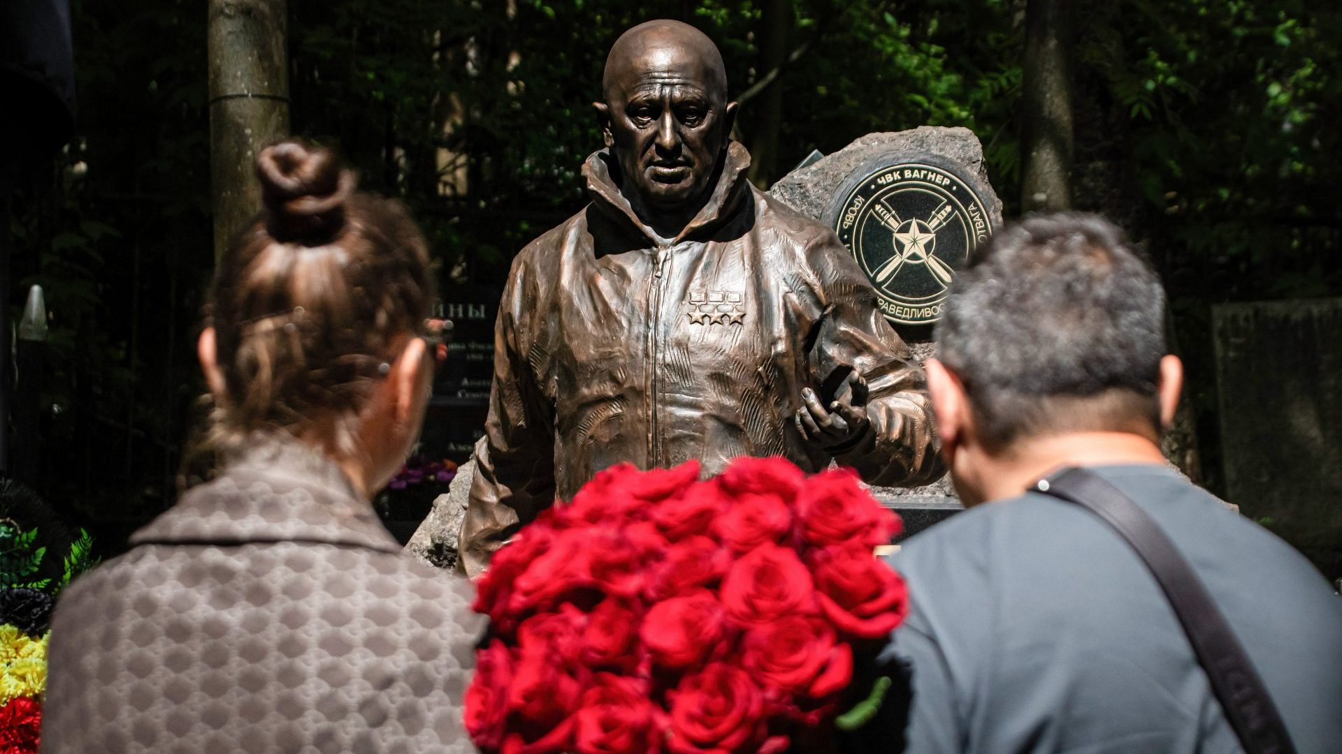 People stand with a bouquet of roses near a sculpture of Russian mercenary leader Yevgeny Prigozhin installed on his grave (Photo by Artem Priakhin/SOPA Images/LightRocket via Getty Images)