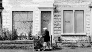 An elderly woman pushes her shopping cart along a derelict street in Lancashire. Photo: Tom Stoddart/Getty