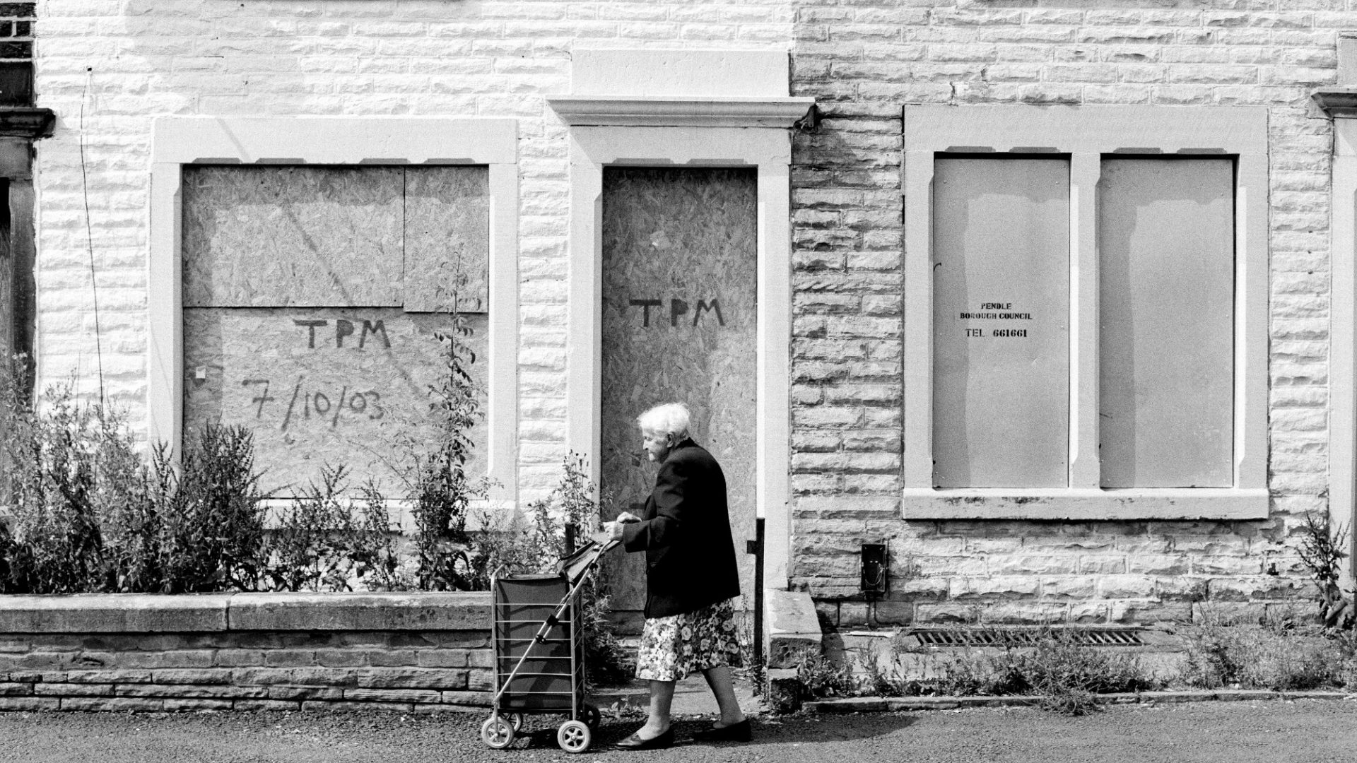 An elderly woman pushes her shopping cart along a derelict street in Lancashire. Photo: Tom Stoddart/Getty