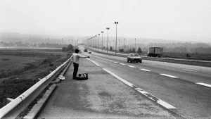 A hitchhiker thumbs a ride on a dual carriageway in central France, 1977. Photo: Julian Yewdall/Getty