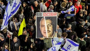 A demonstrator in Tel Aviv holds a sign comparing Benjamin Netanyahu to the late Colombian drug lord Pablo Escobar during a rally by the relatives of Israeli hostages in Gaza. Photo: Jack Guez/AFP/Getty