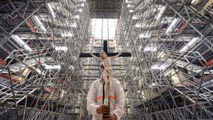 A crucifix is held aloft during a Good Friday meditation prayer amid the scaffolding in Notre Dame on April 15, 2022, marking the third anniversary of the fire that partially destroyed the cathedral. Photo: partially destroyed 
the cathedral. Photo: Bertrand Guay/AFP/Getty