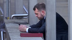 Jonathan Gullis uses his mobile phone as he leans on a wall outside the Houses of Parliament (Photo by JUSTIN TALLIS/AFP via Getty Images)