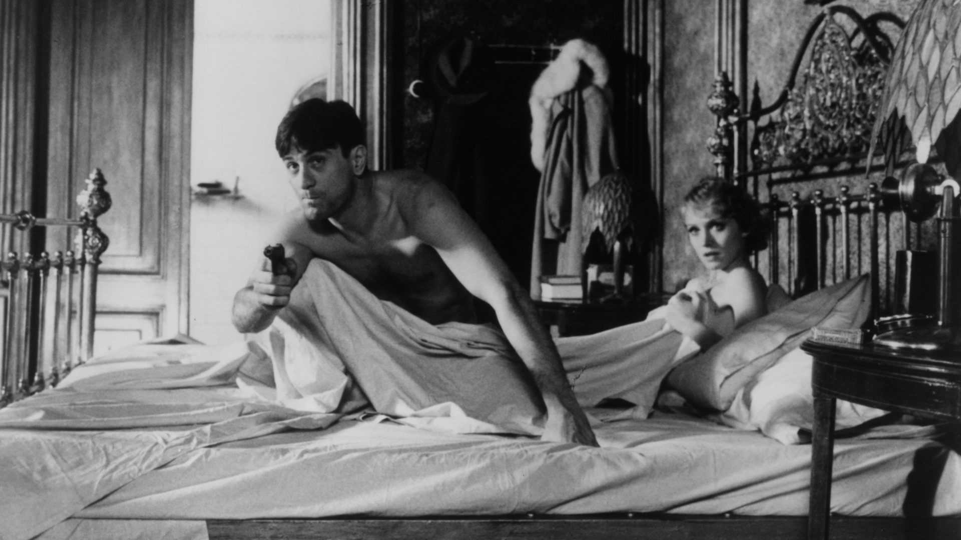 Robert De Niro aiming gun from his bed with Darlanne Fluegel in a scene from the film 'Once Upon A Time In America', 1984. (Photo by Warner Brothers/Getty Images)