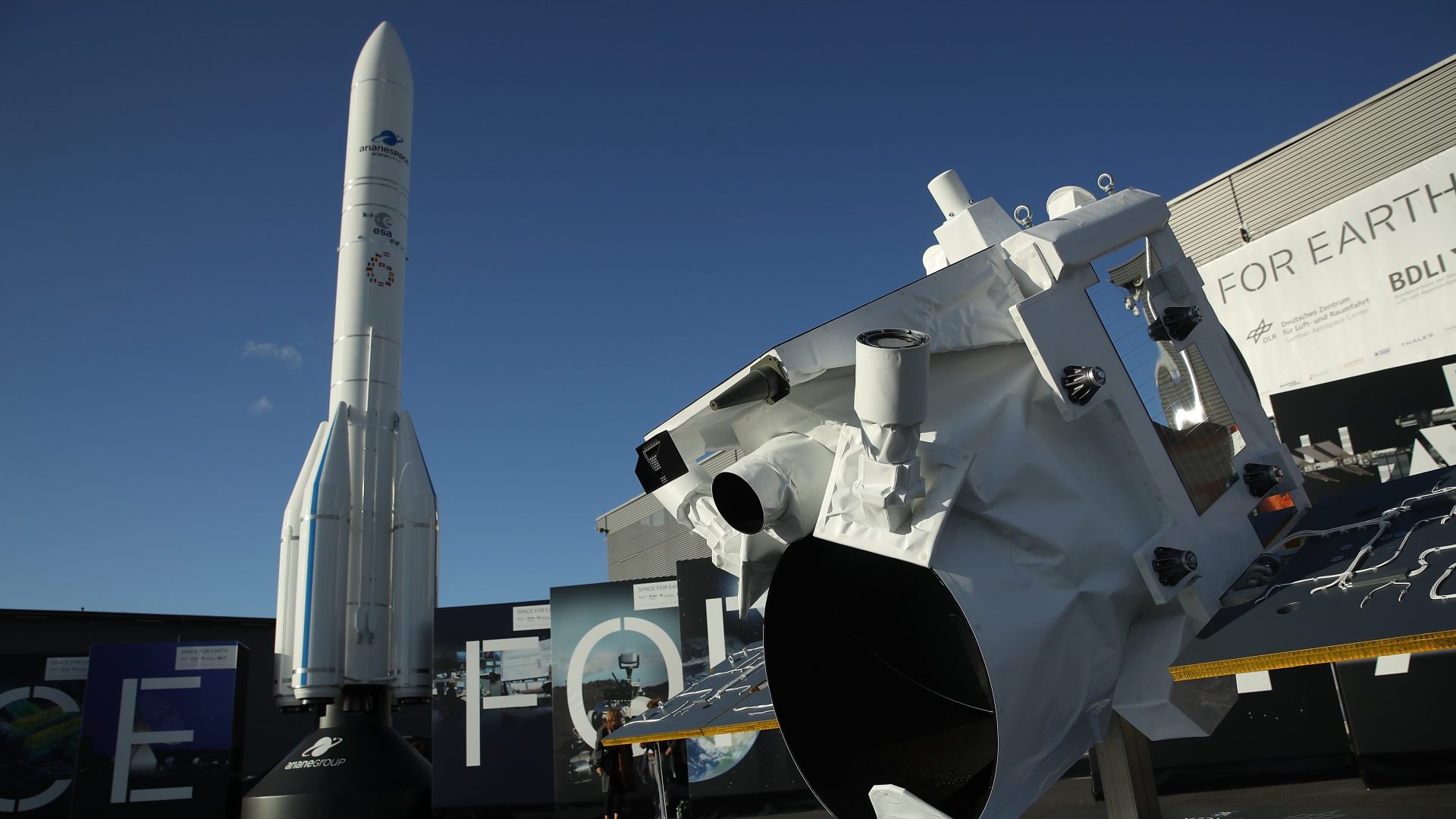 An Ariane rocket and a Merlin satellite stand on display outside the Space Pavillion at the 2018 ILA Berlin Air Show (Photo by Sean Gallup/Getty Images)