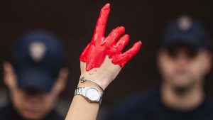 A protester faces with Serbia's police officers showing a red painted hand symbolising government neglect and mismanagement. Photo: ANDREJ ISAKOVIC/AFP via Getty Images